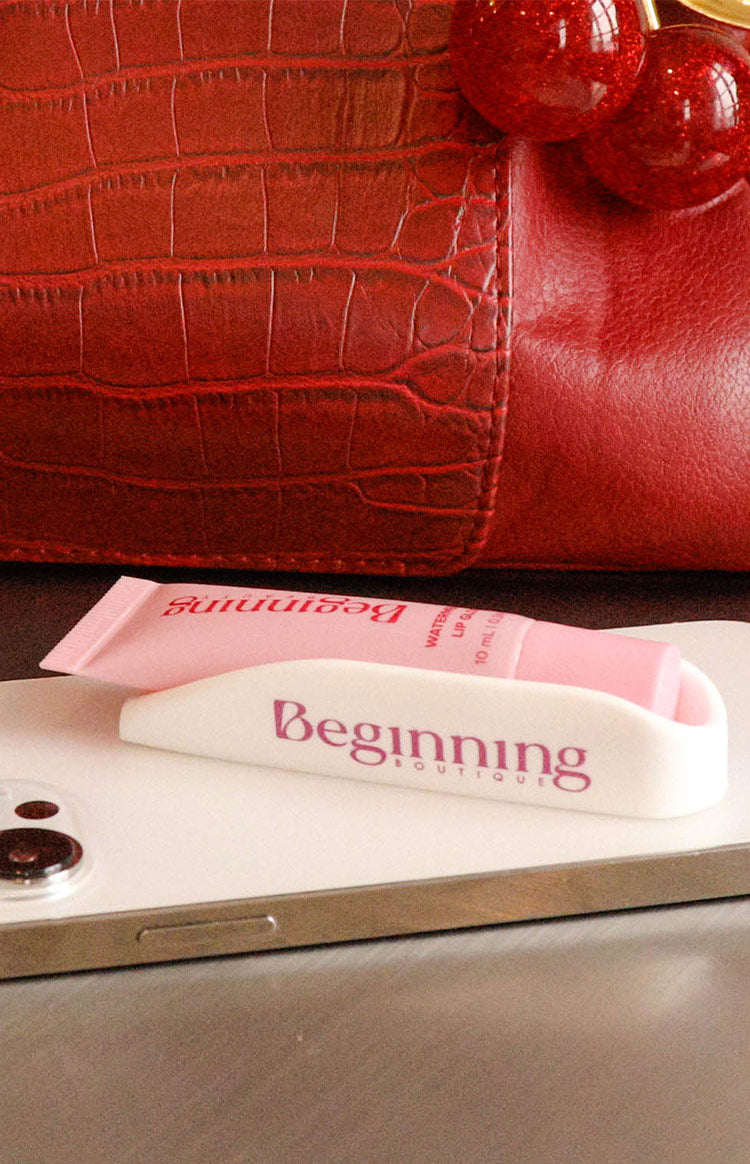 White phone holder with a pink lip gloss tube inside