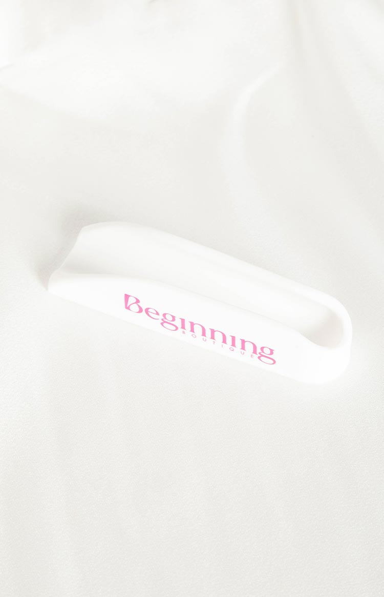 White silicone phone holder with pink Beginning Boutique logo on the front