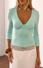 Turquoise jersey top with a deep V-neck, 3/4 sleeves, and fitted bodice with under-bust shaping