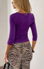 Rear view of a purple jersey top with 3/4 sleeves and a fitted silhouette