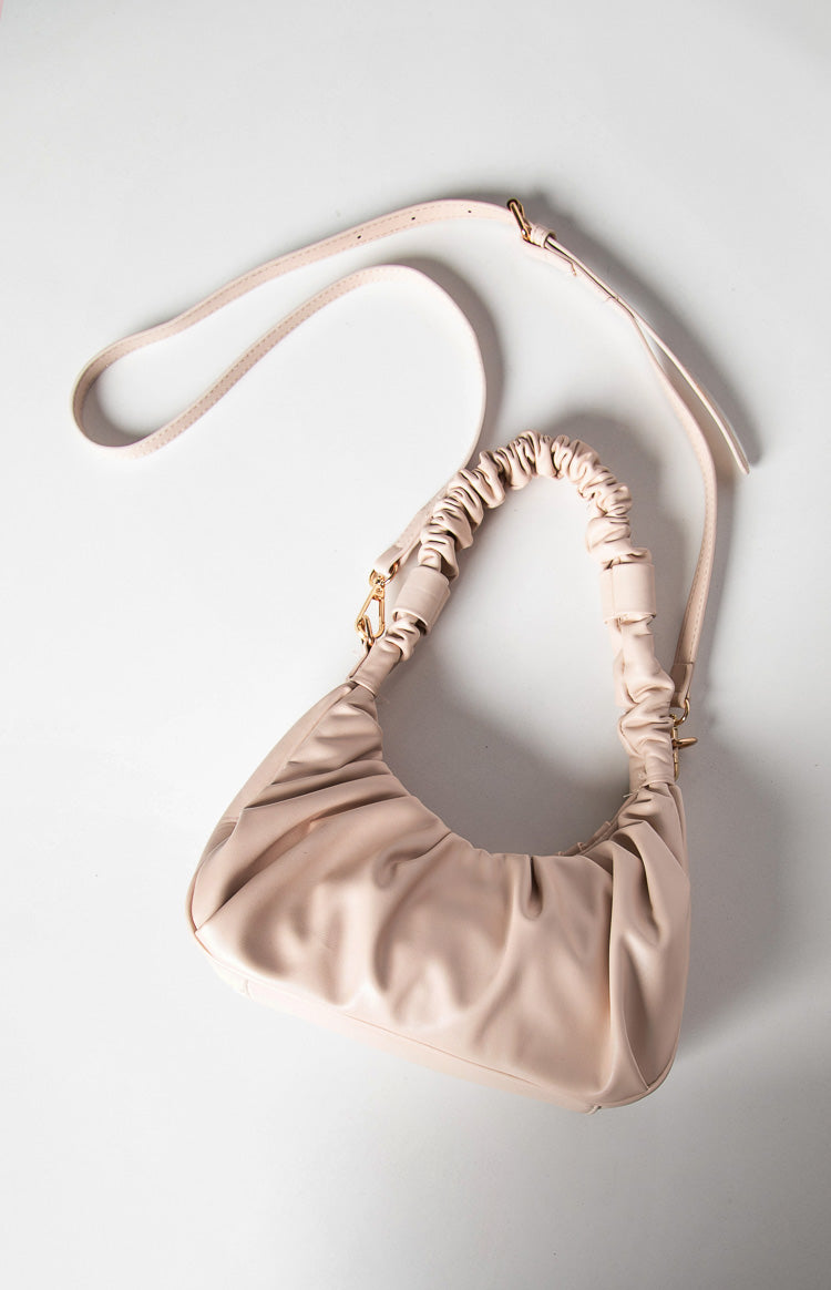 Cream handbag with a ruched short strap and a long adjustable crossbody strap with gold hardware