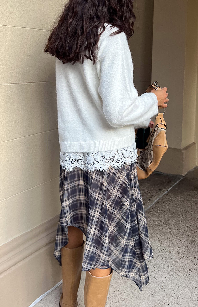 Side view of a cream fuzzy knit with a wide white lace trim visible at the bottom hem