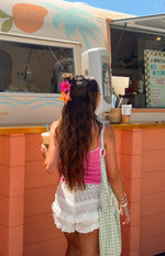 Rear-side view of white knit ruffle shorts with tiered ruffles and open-knit crochet panels
