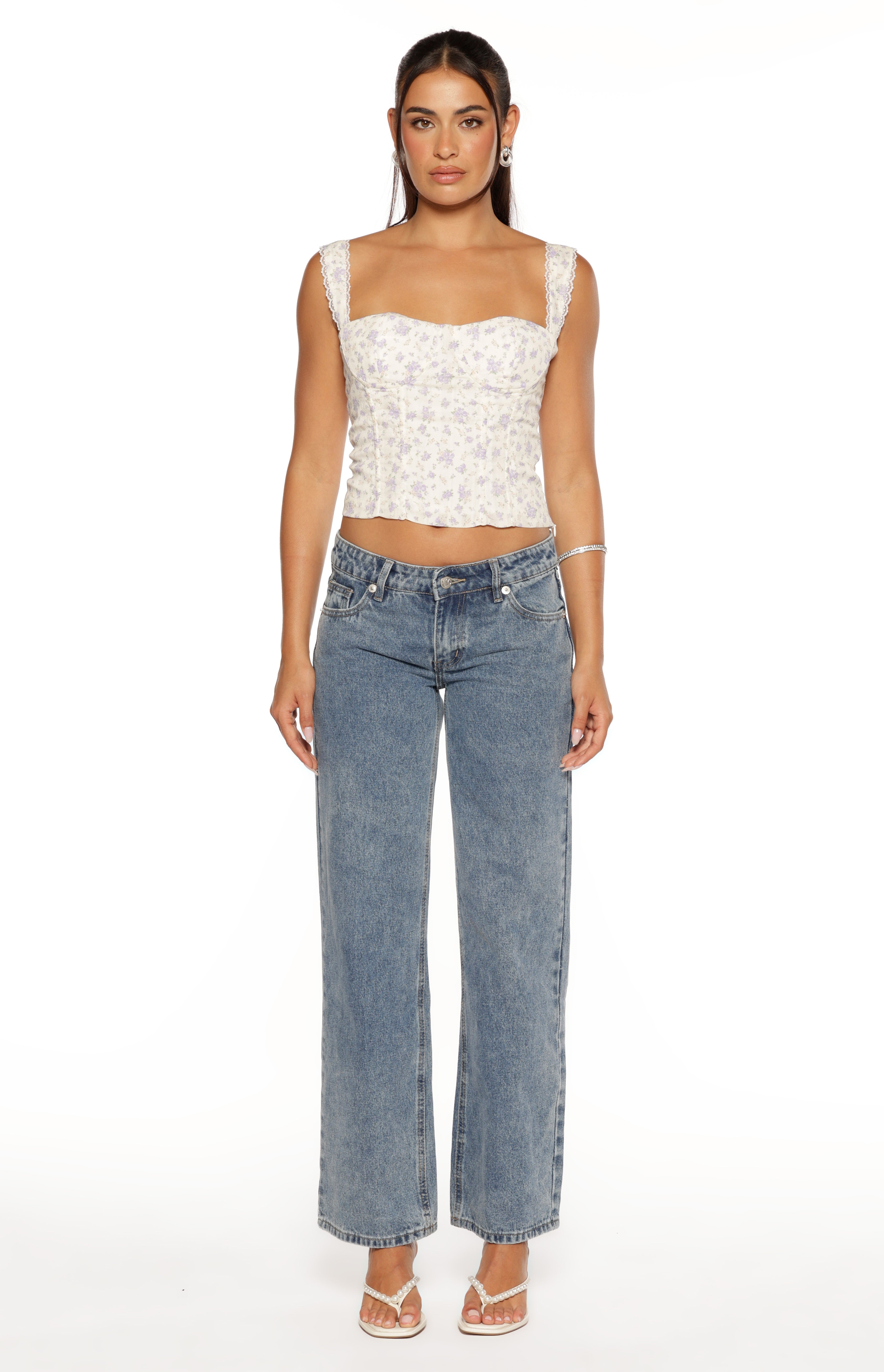 Front view of a white floral corset top with purple flowers, a square neckline, lace-trimmed straps, and a cropped fit