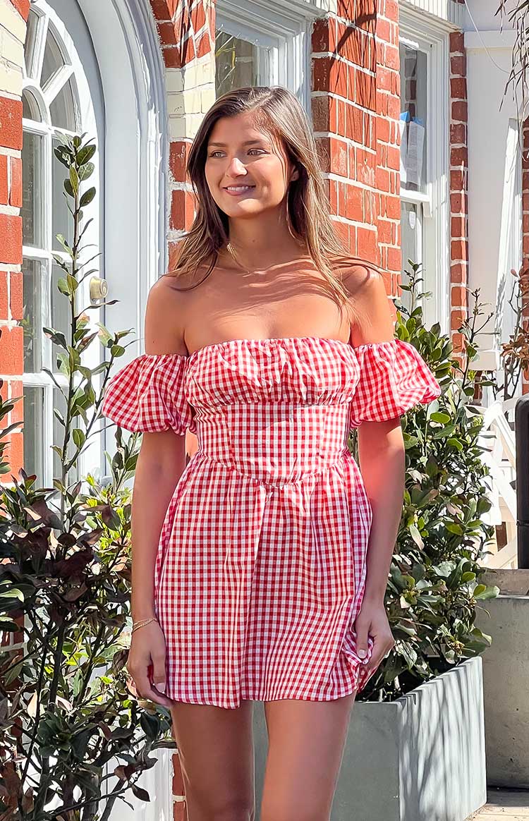 Off-shoulder red gingham mini dress with a gathered bust, short puff sleeves, and fitted waist