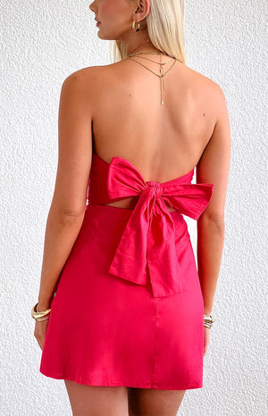 Rear view of the red strapless mini dress featuring a large bow tie back and waist cutout