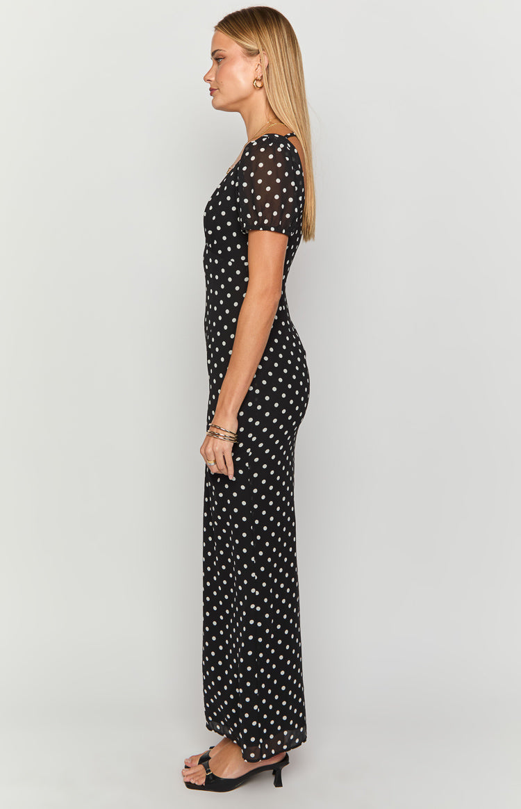 Side view of a black polka dot maxi dress with short puff sleeves and a fitted silhouette