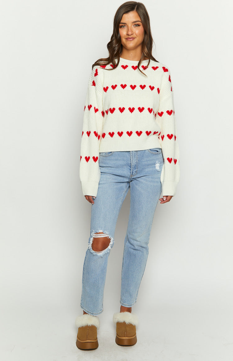 Cream knit jumper with horizontal red heart pattern, ribbed crew neck, and relaxed fit