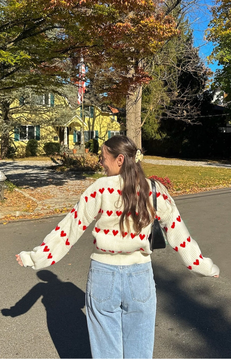 Rear and side view of a cream knit jumper with red heart pattern and ribbed cuffs and hem