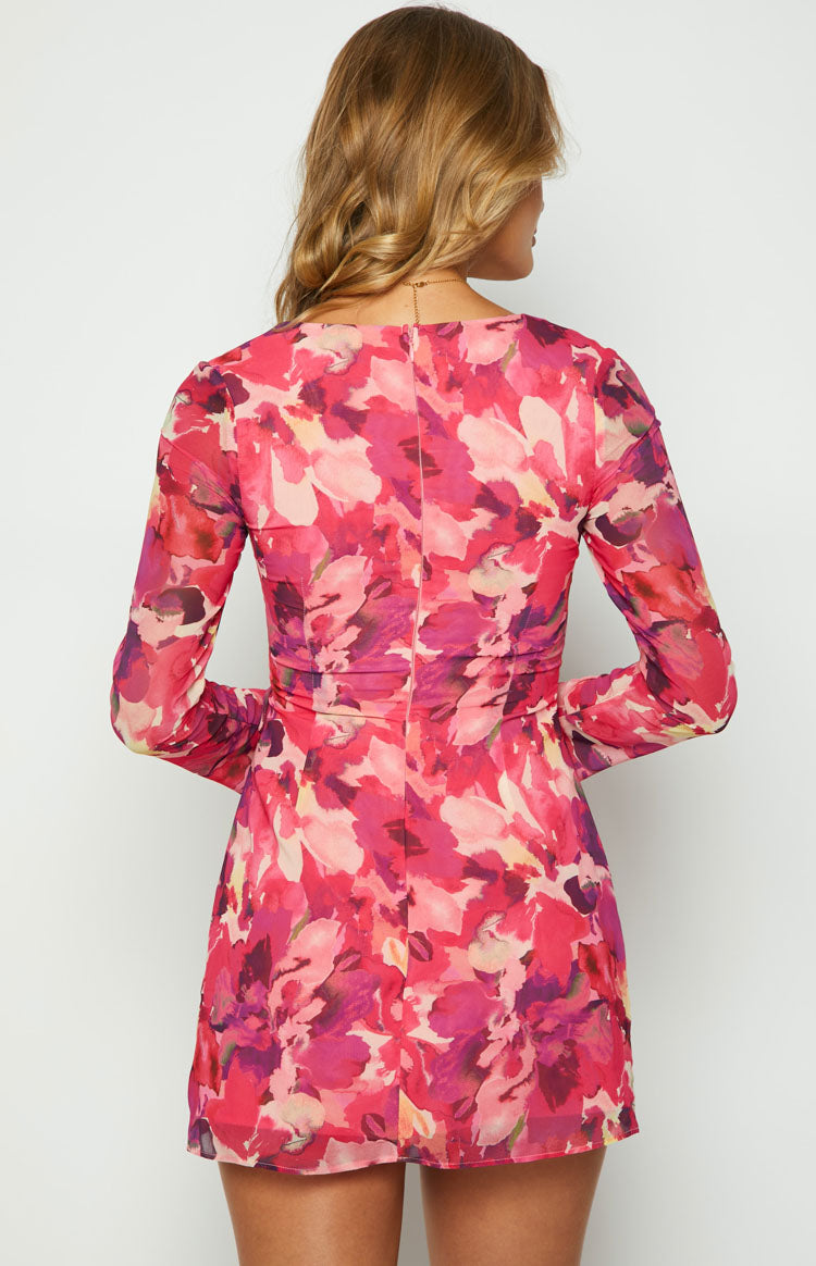 Rear view of a pink floral long sleeve mini dress with a subtle back zipper and ruched waist detail