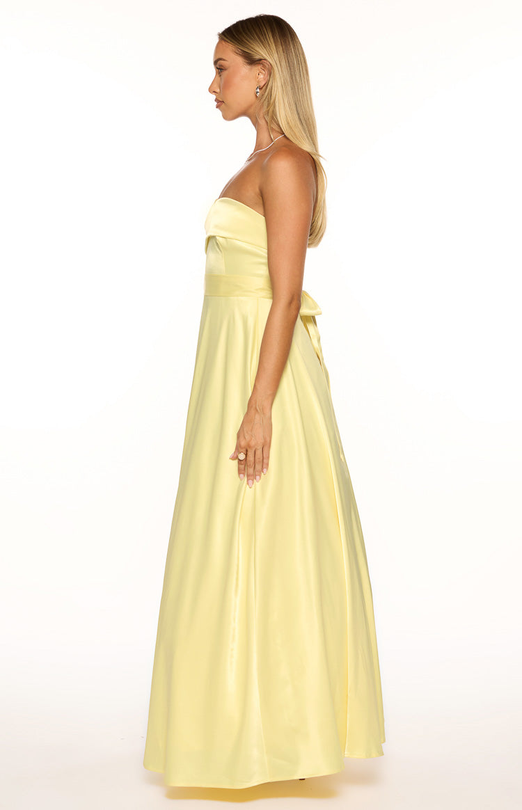 Side view of a yellow satin strapless maxi dress with a fitted waist and a tie detail at the back