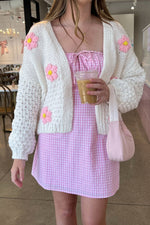 White chunky knit cardigan with pink and yellow flower appliques and voluminous long sleeves