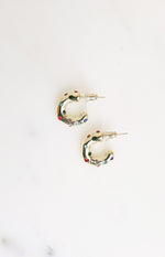 Flat lay of two gold mini hoop earrings with scattered red, green, blue, and pink stones and stud backs