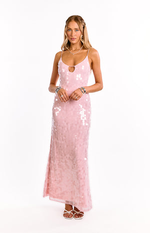 Model wears a sparkling pink sequin maxi dress. This glamorous formal gown has a v-neckline and a leg split. A perfect dress for a birthday celebration or New Years Eve party.