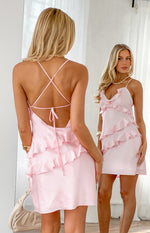 Rear view of a pink mini dress with criss-cross spaghetti straps, tie-back, and tiered ruffles
