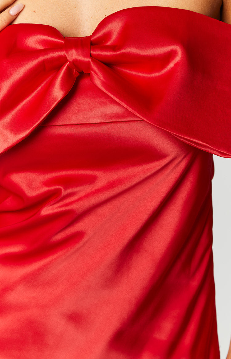 Close-up of the large red satin bow detail on the off-shoulder mini dress, showing the shiny fabric
