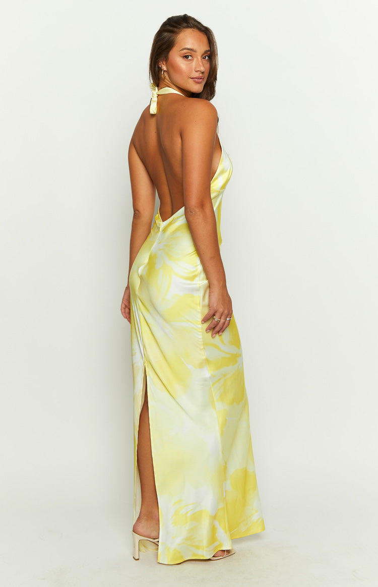 Rear-side view of a yellow and white abstract print satin maxi dress with a tie-halter neck, open back, and high side slit