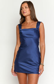 Close-up of the square neckline and ruched wide straps on a navy satin mini dress