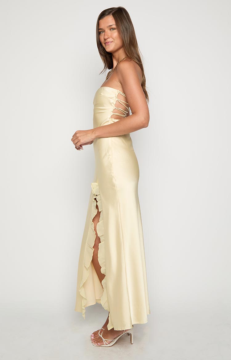 Side view of a yellow maxi dress showing the lace-up side cutouts and high leg slit with ruffle trim