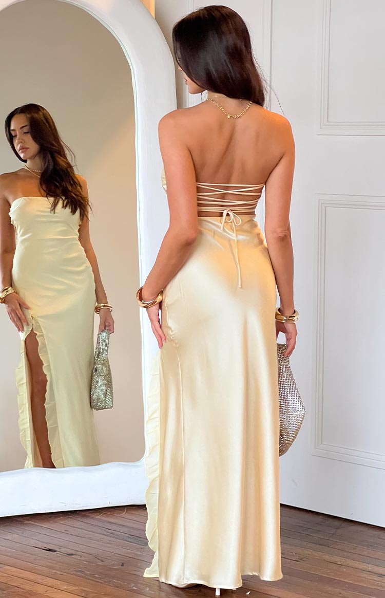 Rear view of a yellow satin strapless maxi dress with a lace-up back detail and a ruffled side slit