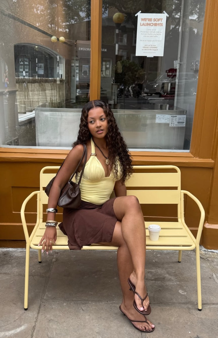 Side view of a brown ruched mini skirt showing the gathered fabric and short length
