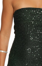 A close-up view focuses on a strapless dress in a emerald green color featuring the entire garments covered in vertical rows of fine sparkling sequins which give the fabric a textured shimmering appearance.