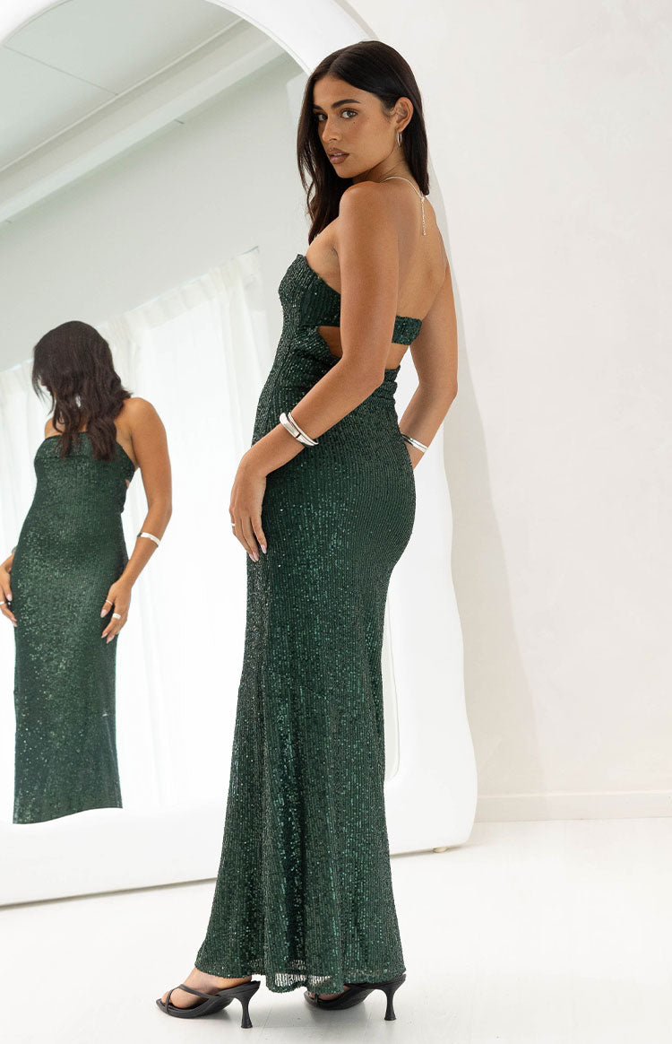 Side view of an emerald green sequin maxi dress with a strapless neckline and side cutout