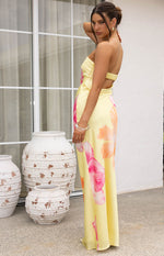 Side view of a yellow hibiscus print maxi dress showing the strapless neckline and back cut-out with shirred elastic strap