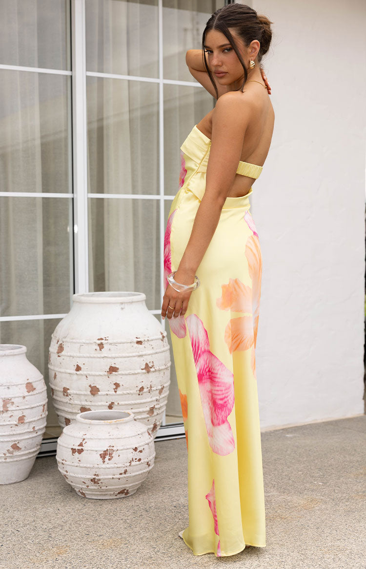 Side view of a yellow hibiscus print maxi dress showing the strapless neckline and back cut-out with shirred elastic strap