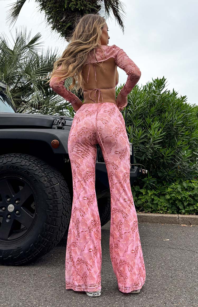 Back view of the pink swirl snake print pants showing the fitted silhouette and wide flared hem