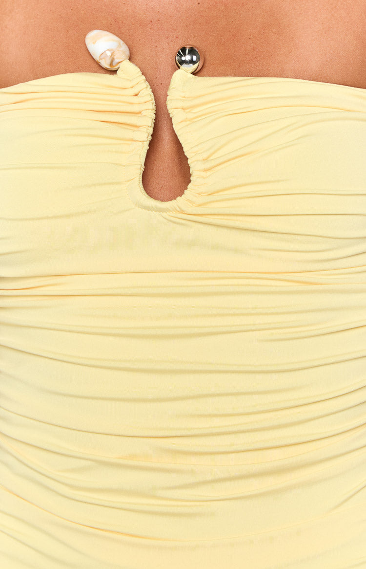 Close-up of the yellow ruched strapless dress showing the cutout neckline with shell and silver bead details