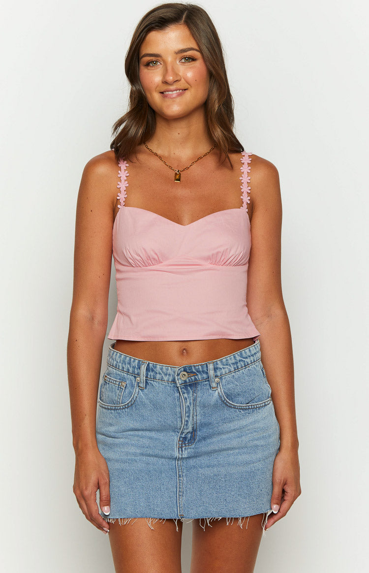 Fitted pink crop top with a sweetheart neckline, ruched bust detail, and flower-embellished shoulder straps