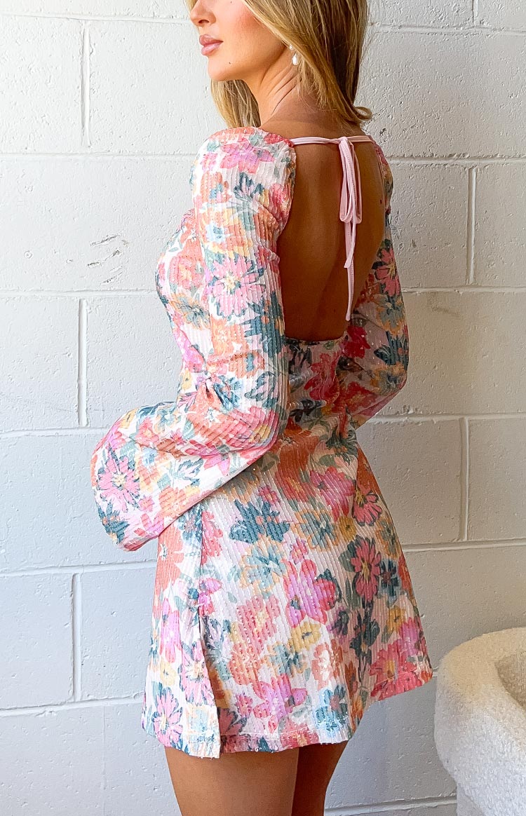 Side view showing the open back with pink tie closure and long sleeves of a floral sequin mini dress