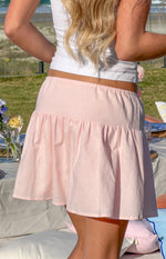 Rear view of a pink mini skirt with an elasticated waist and gathered tiered hem