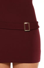 Close-up of the gold rectangular buckle detail on the waist of the burgundy micro mini dress