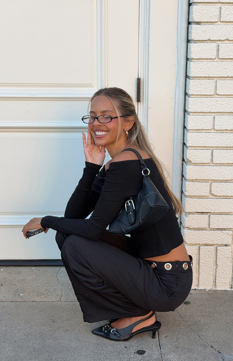 A close-up of a fitted black long-sleeve crop top with an off-the-shoulder neckline.