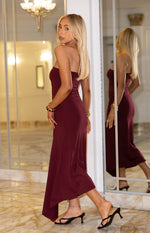 Side view of a plum strapless midi dress with a fitted bodice and flowing asymmetrical hem