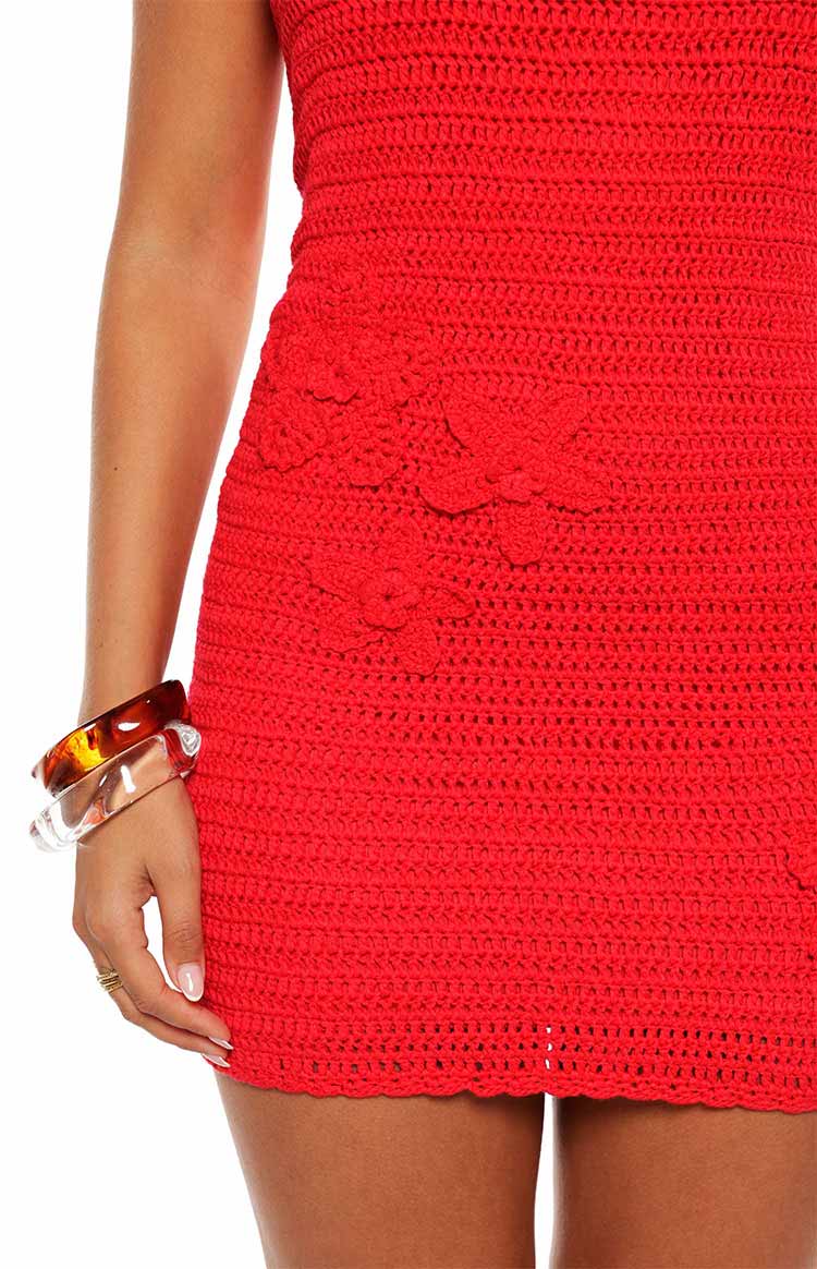 Close-up of the red crochet mini dress showing the floral appliques and scalloped hem