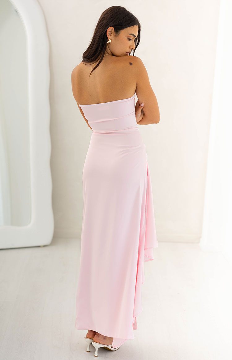 Rear view of a light pink strapless maxi dress with a fitted bodice, ruched side, and layered flowy skirt