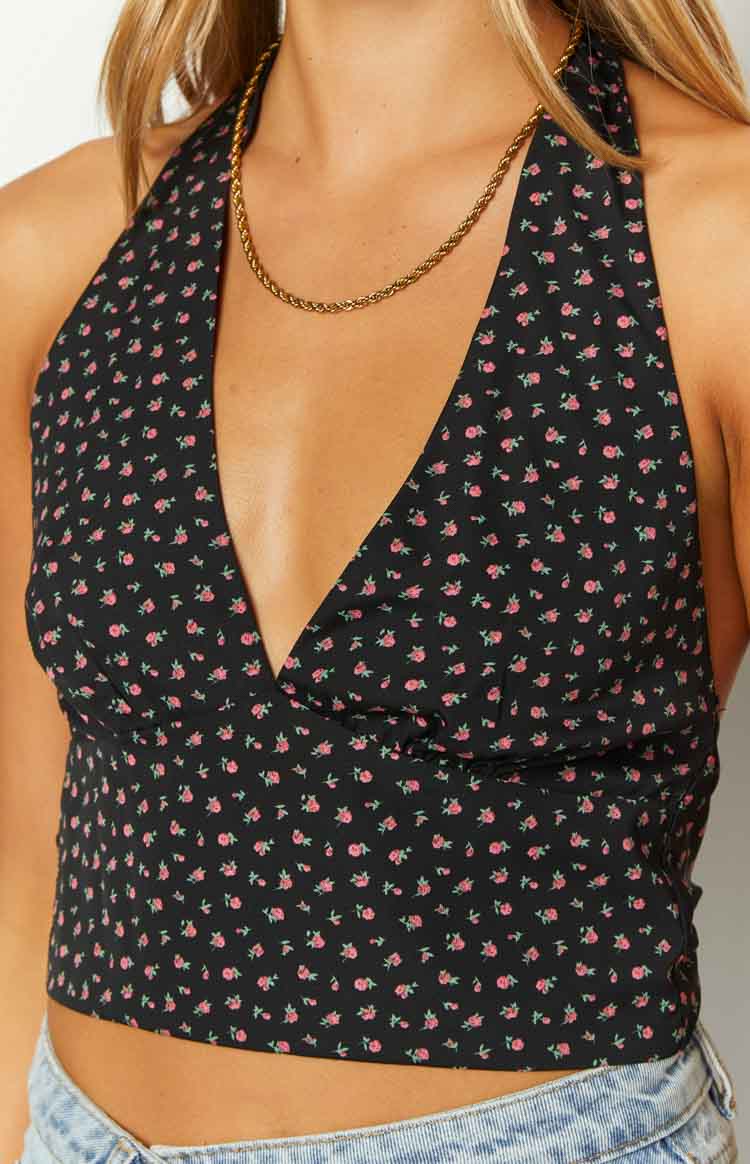 Close-up of the deep V-neck halter neckline and small pink floral print on a black crop top