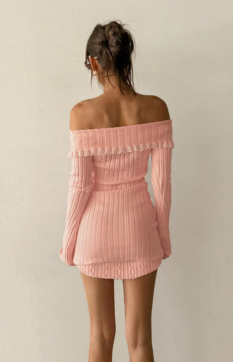 Back view of a pink ribbed knit off-shoulder mini dress with ruffled lace trim and cable knit hem