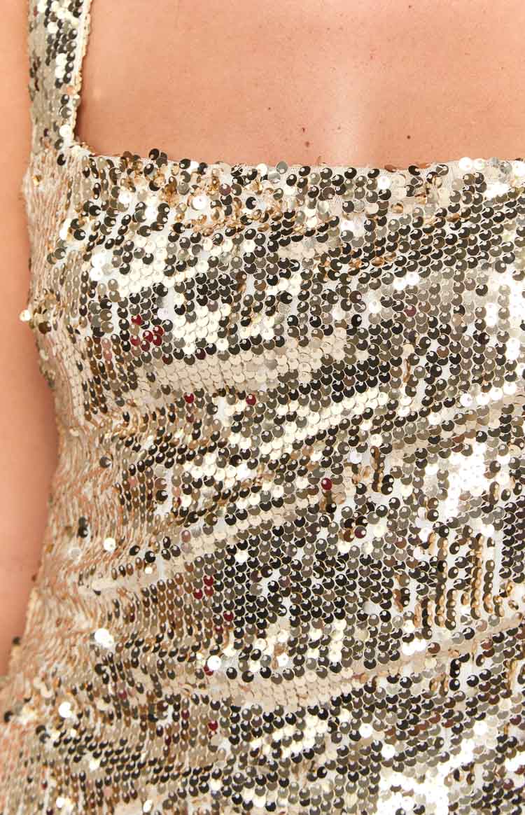 Close-up of the shimmering gold sequin fabric and square neckline of the maxi dress