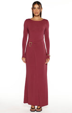 Front view of a burgundy long sleeve maxi dress with a boat neck and a gold buckle detail creating a wrap effect