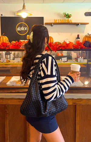 Side view of a navy and white striped knit sweater showing the pattern on the long sleeves