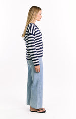 Side view of a navy and white striped knit sweater with long sleeves and a relaxed fit