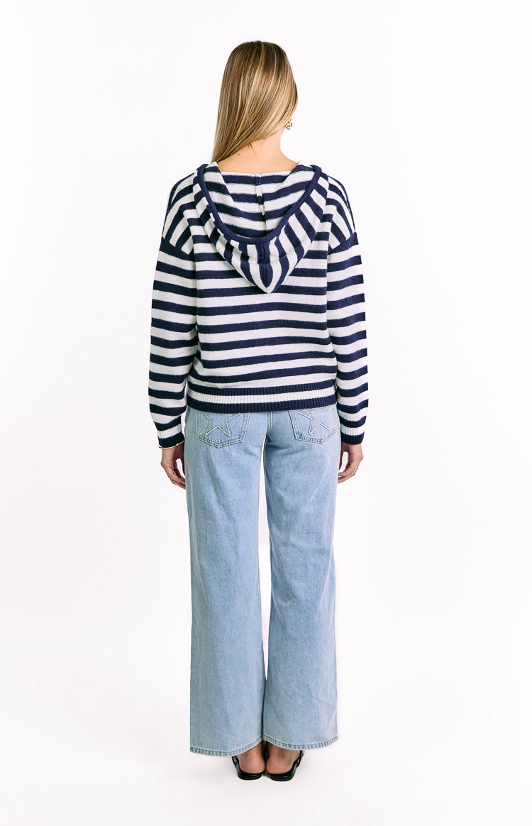 Rear view of a navy and white striped knit sweater with a hood and ribbed hem