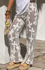 Close-up of white sheer wide-leg pants with an embroidered floral pattern