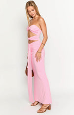 Side view of a pink strapless maxi dress with twisted bust, waist cutouts, and a long tie detail