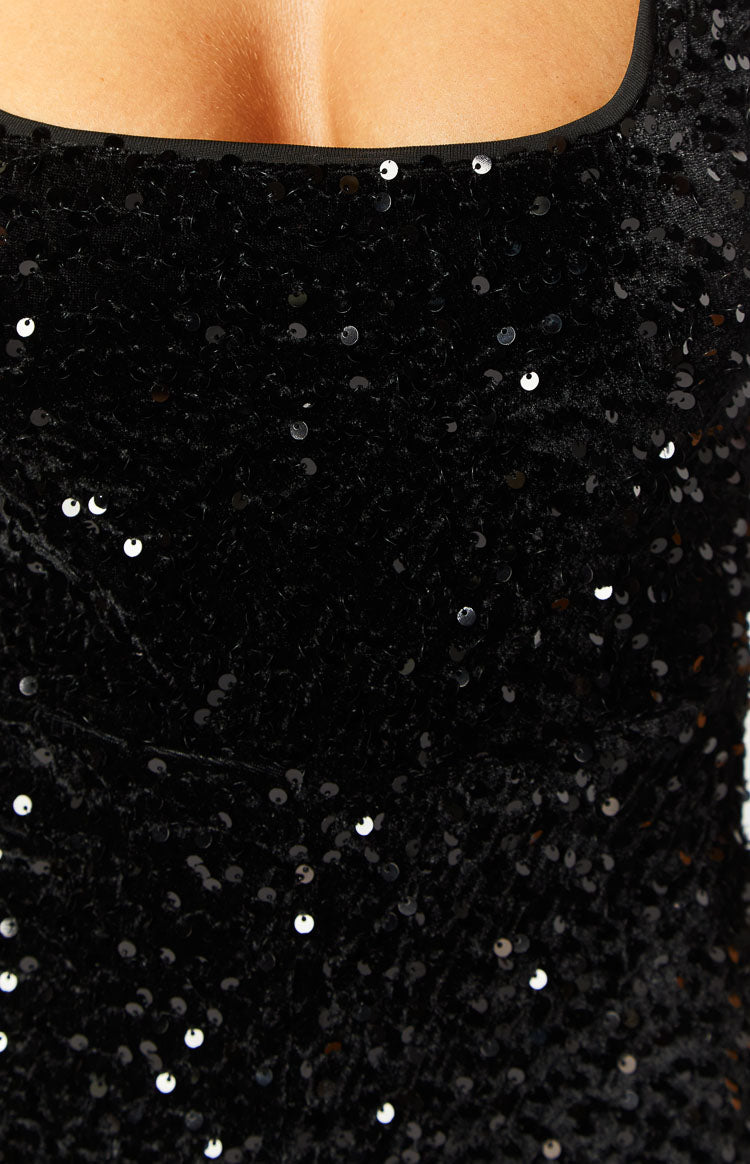 Close-up of the black sequin fabric with neckline binding showing individual sequins and the textured base of the playsuit