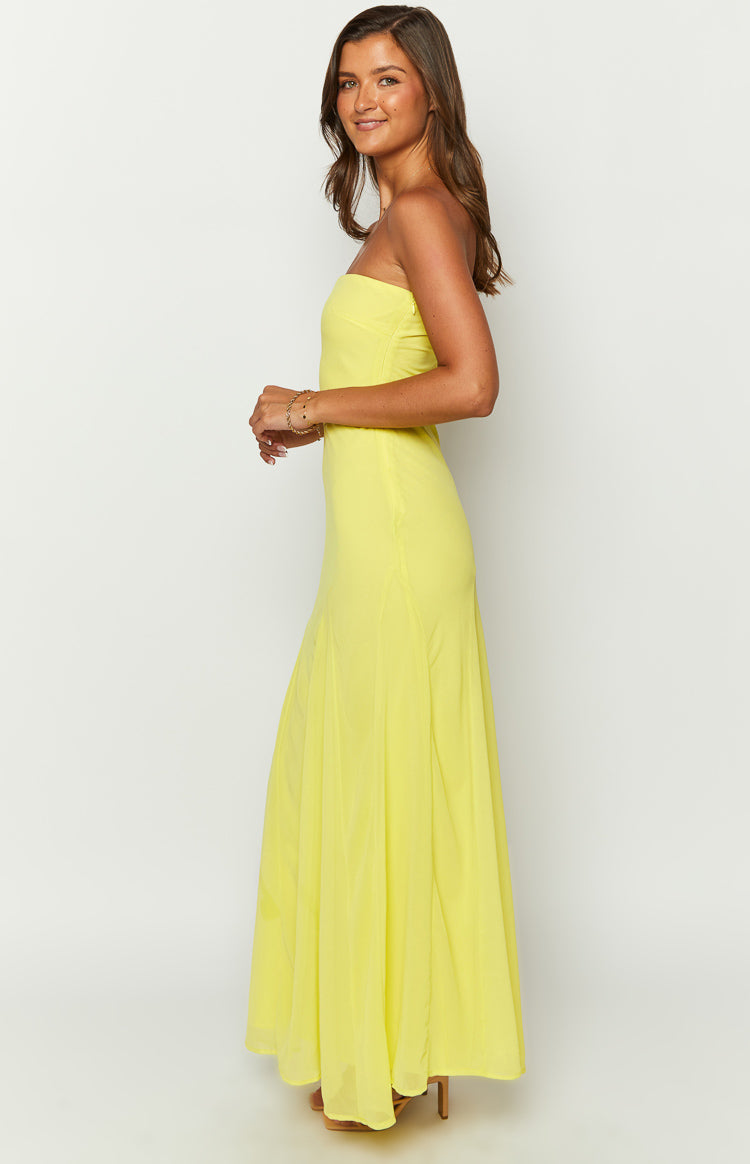 Side view of a yellow strapless maxi dress with a fitted bodice and a flowy skirt